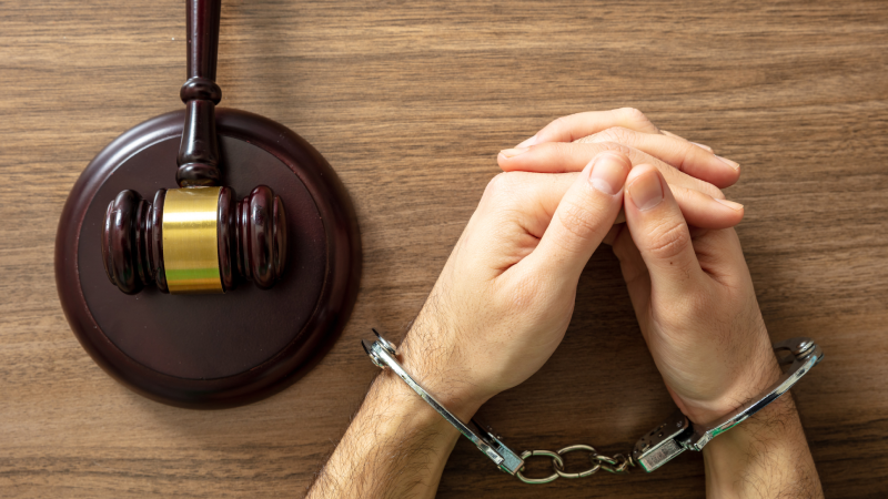 Handcuffed Convict, Law offender and Justice. Court sentence Prison. Handcuff locked and judge gavel on a wooden table, top view.