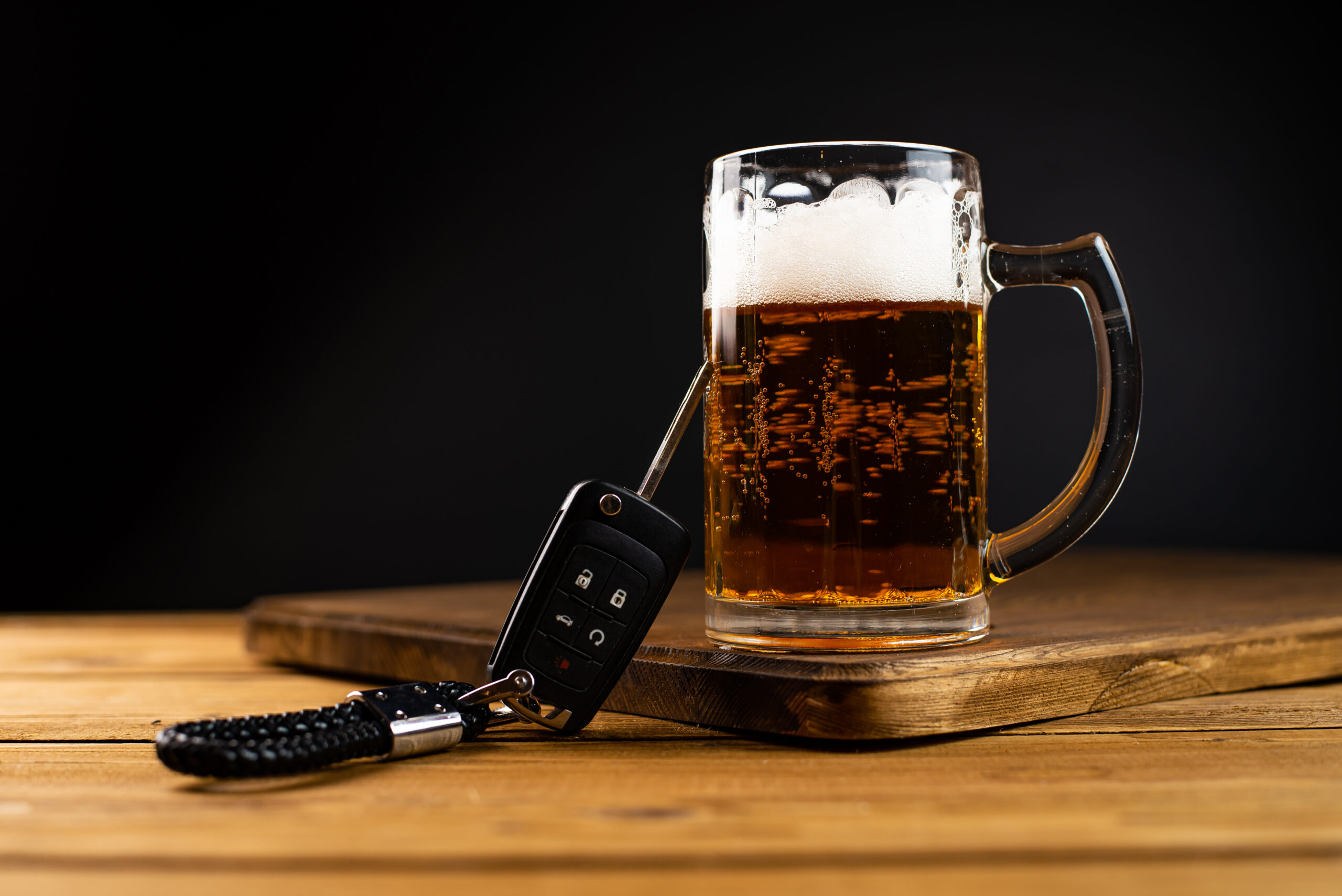 Drinking and driving concept. Car key on a wooden table, pub background