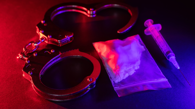 Drug smuggling and trafficking and handcuffs and bags of cocaine on black background. Business with illegal substances and arrest