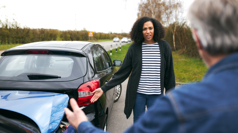 Senior male driver arguing over blame for car accident with a younger female motorist