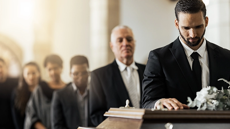 Man in suit mourning at a casket.