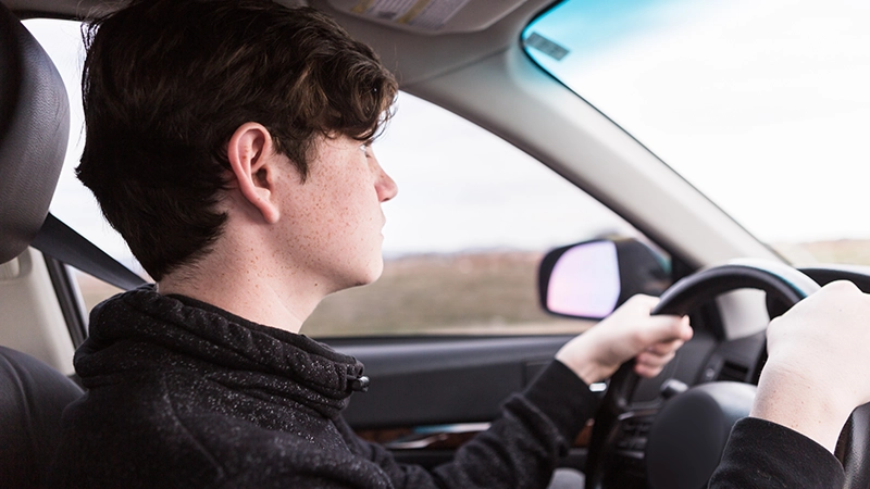 A young male driving a car.