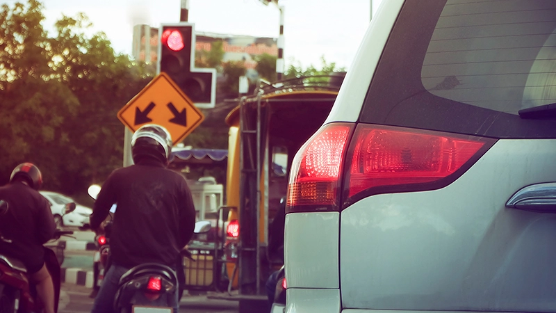Car tail light and motorcycles at red light.