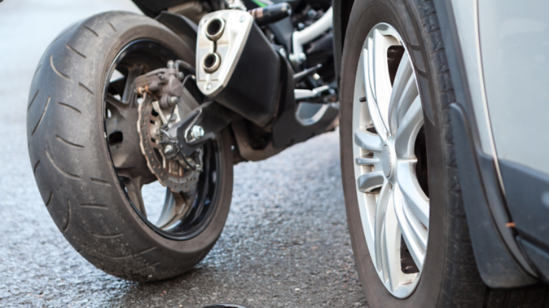 Motorcycle accident close-up view, broken parts laying on asphalt road