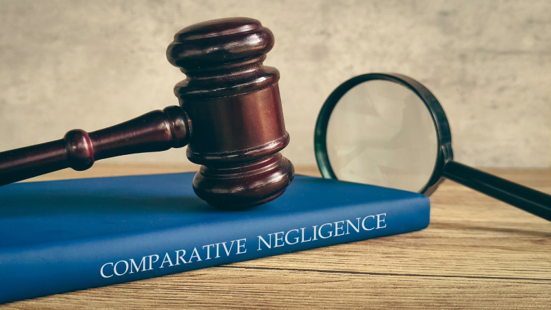 A gavel and magnifying glass on a book titled "COMPARATIVE NEGLIGENCE," symbolizing a legal investigation