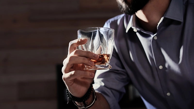 Man with glass of whiskey at home.