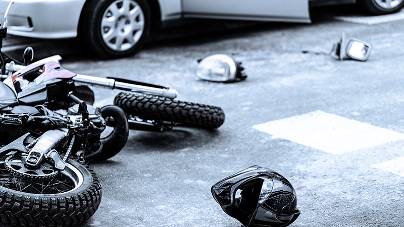 Helmet and motorcycle on the street after car crash.