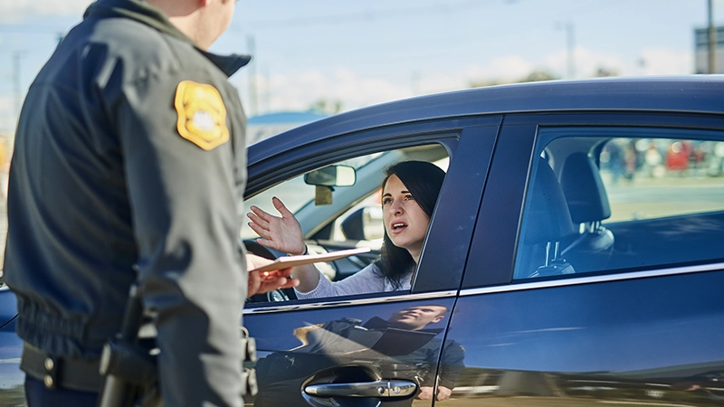 Upset woman receiving a ticket from a traffic officer at a highway checkpoint.