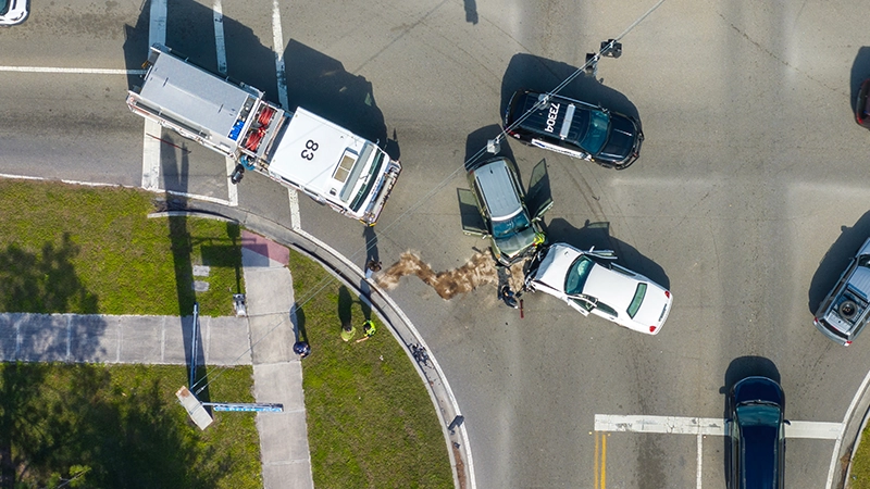 Emergency services personnel helping victims of car crash on city street.