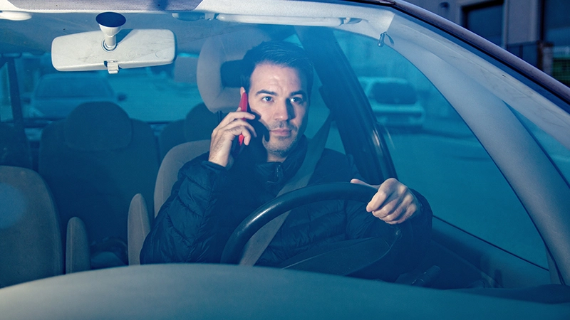 Driver distracted using mobile phone while driving car.