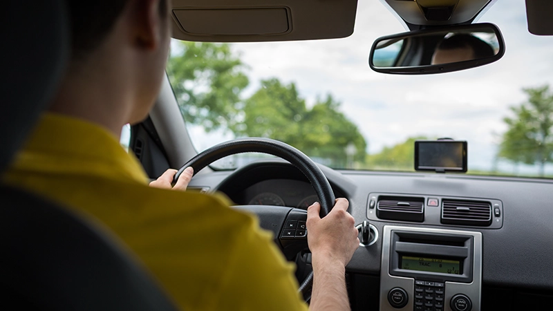 Man driving a car with his hands on the steering wheel.