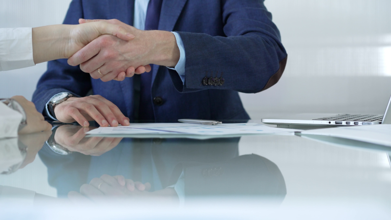 Business people shaking hands at the glass table after reaching an agreement during a meeting